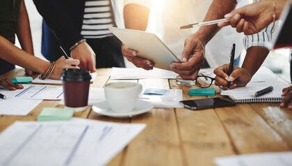 Group of people standing around a table discussing ideas