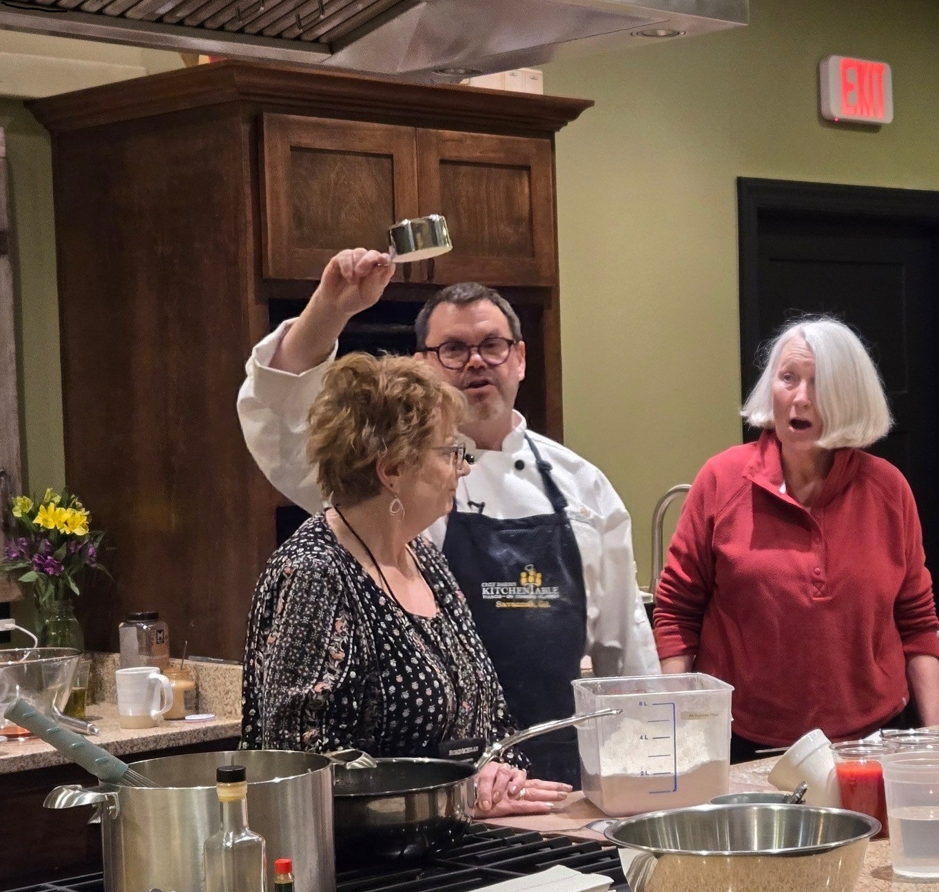 The chef demonstrates measuring a cup of flour with Kathryn