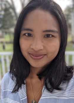 Headshot of Elizabeth Hansen wearing blue striped shirt and trees blurred in the background