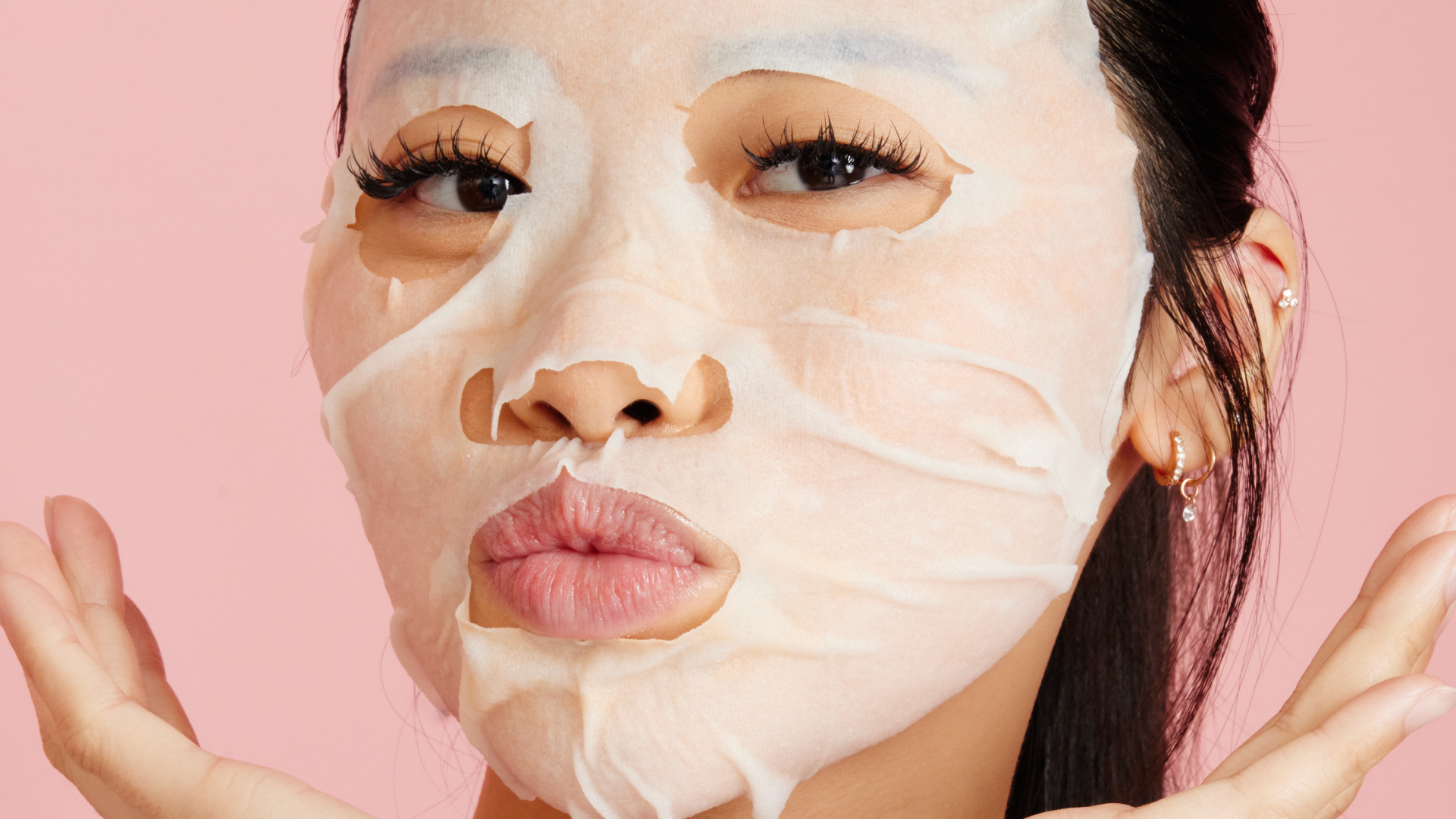Girl with a white face mask holding her hands to her face and pouting
