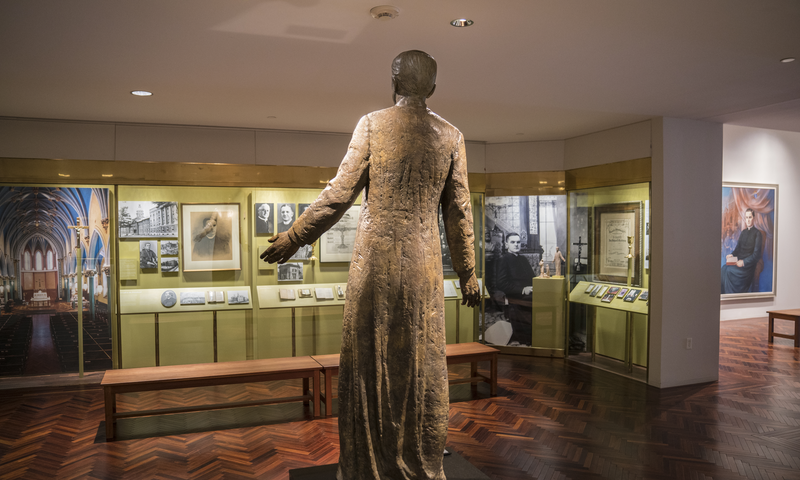 Photo of the Father Michael J. McGivney Gallery looking from behind the bronze statue of McGivney toward the cases, October 19, 2017.