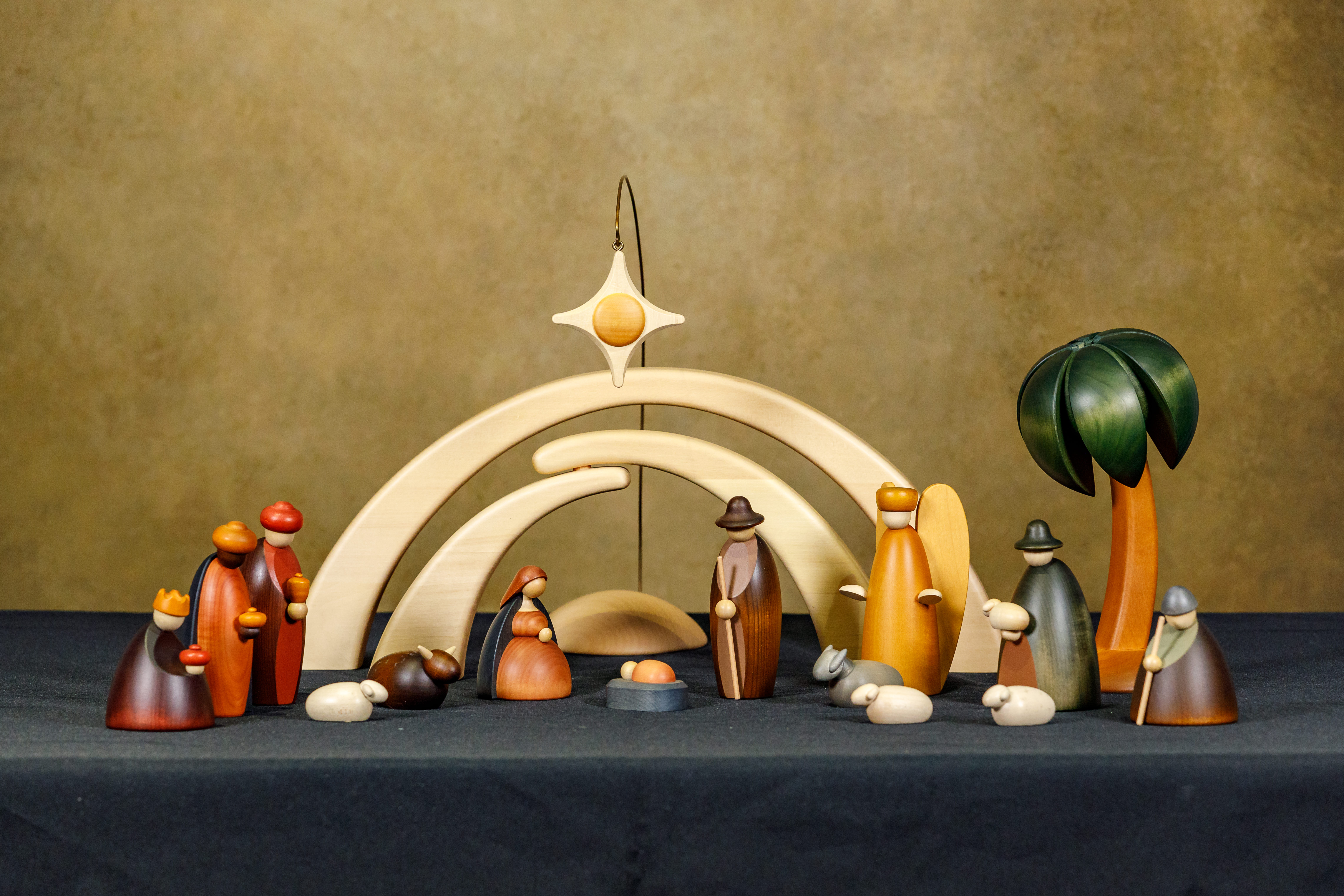 Wood painted Nativity from Germany with the Holy Family, angel, 2 Magi, 2 shepherds, 3 sheep, an ox, a donkey, a palm tree, 2 arches, and a star.