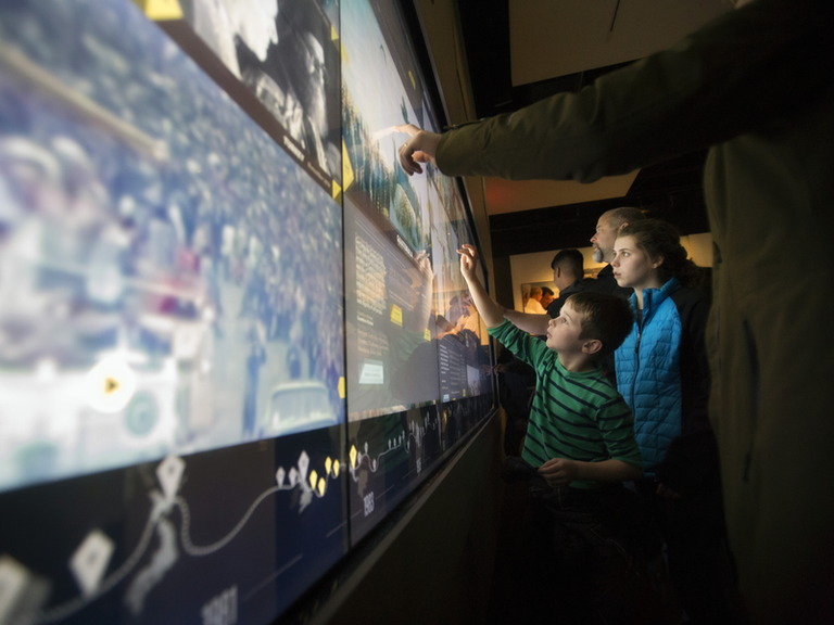 Pligrims touch the interative screen in the Shrine's exhibit of the life of Saint John Paul II. 