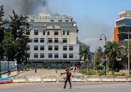 Smoke billows from the Ministry of Finance Building near the National Palace in Port-au-Prince, Haiti, as people walk through the area on April 2. Police engaged in a prolonged battle with armed gangs in the latest of a series of attacks on government infrastructure. (AP Photo/Odelyn Joseph)