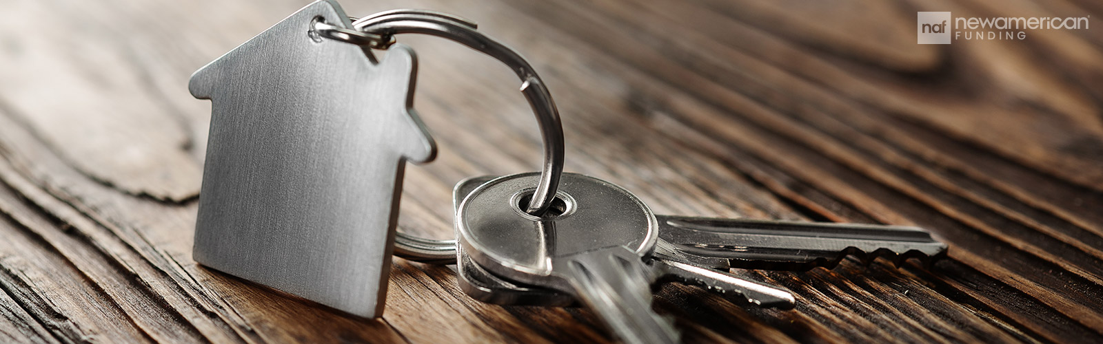 silver keys with a small house key chain sit on a table