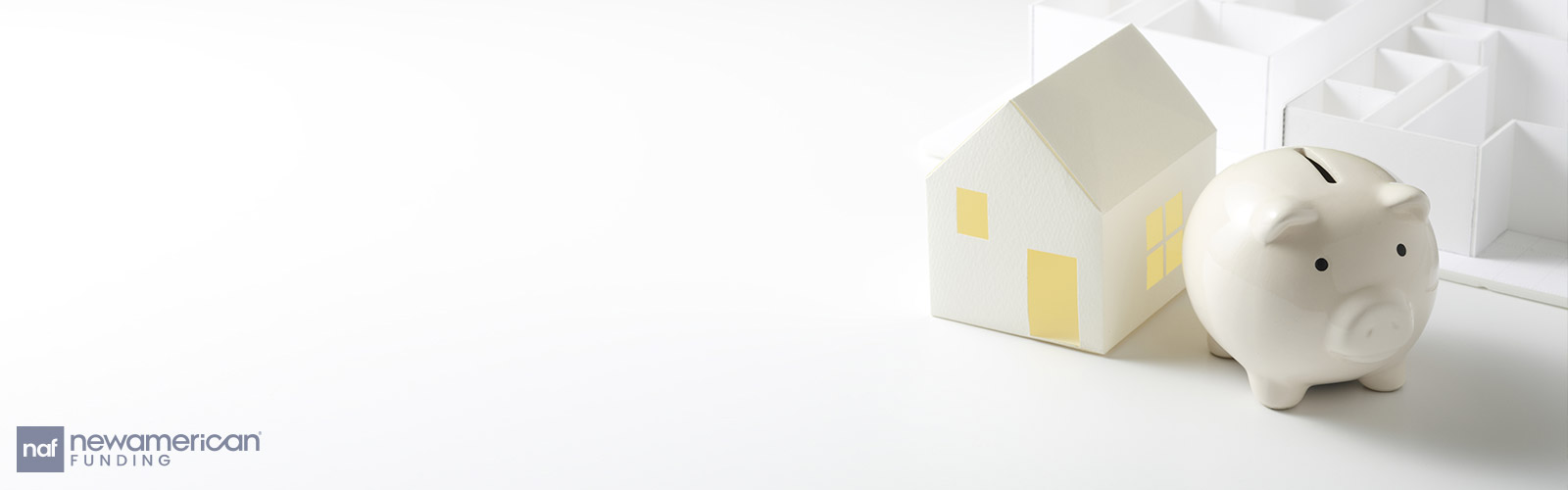 A small model house and a piggy bank sit on a table top