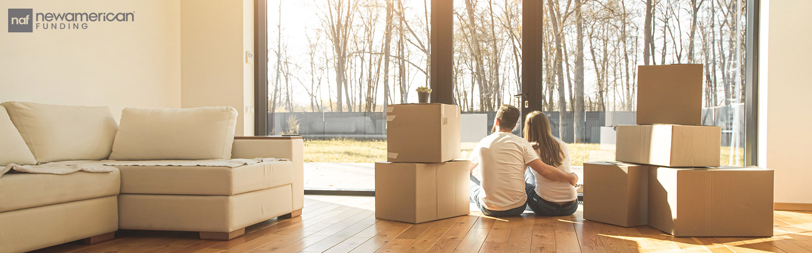 couple sitting on the floor and looking into yard of their new house surrounded by moving boxes