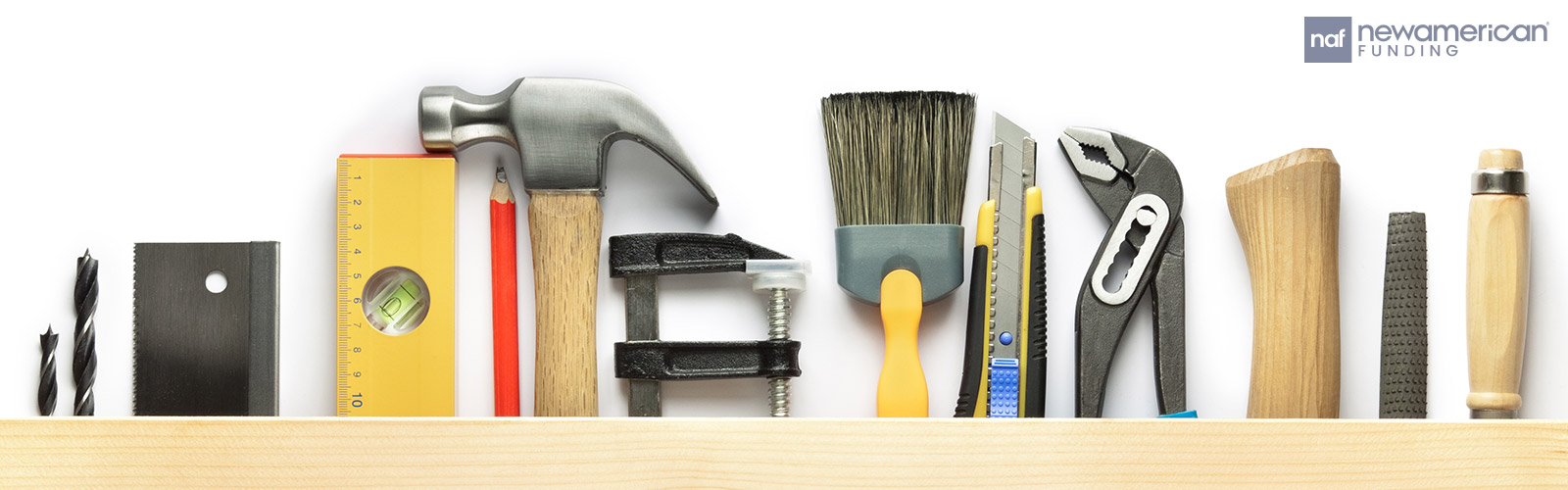 Home tools lined up next to each other including a paint brush, a hammer, a screwdriver etc. 
