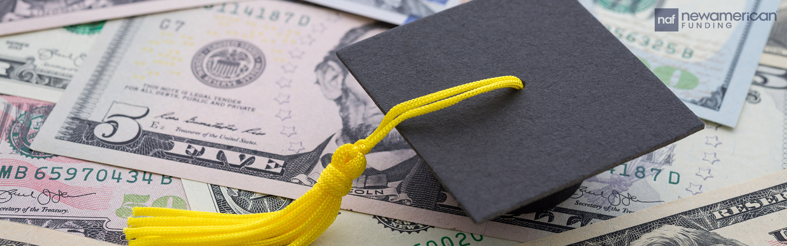 A graduation cap sits on top of a pile of cash
