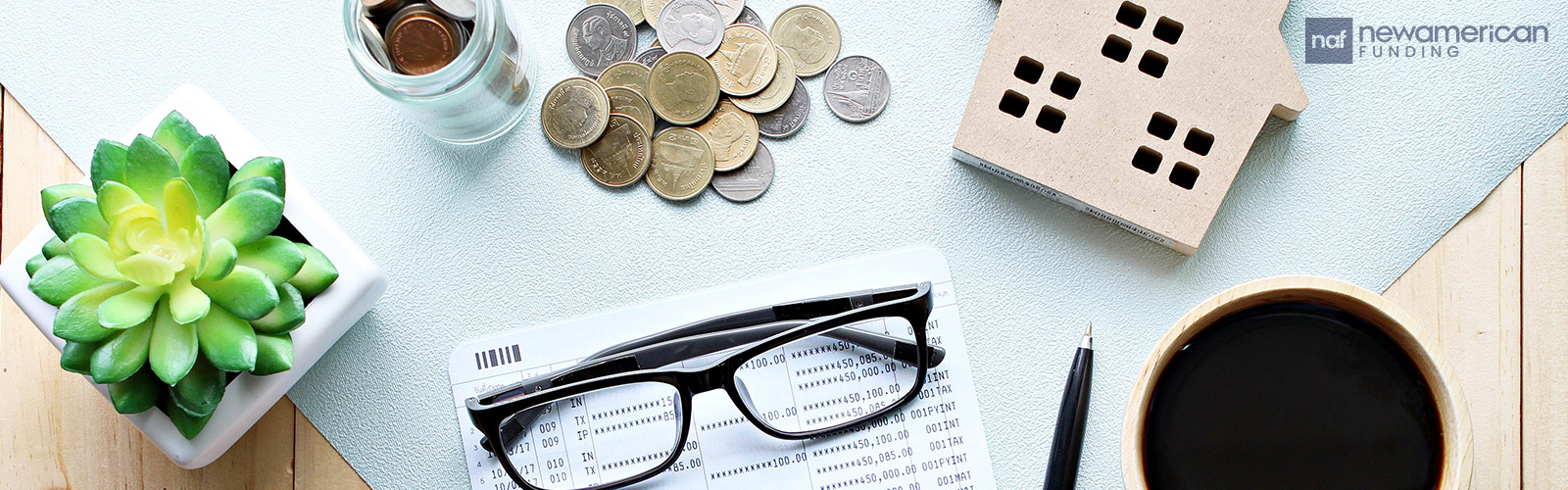 Various objects sit on top of a desk including glasses, coins, a model of a house, and coffee