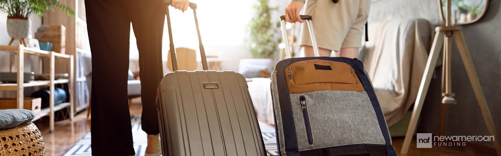Two people rolling suitcases into a home