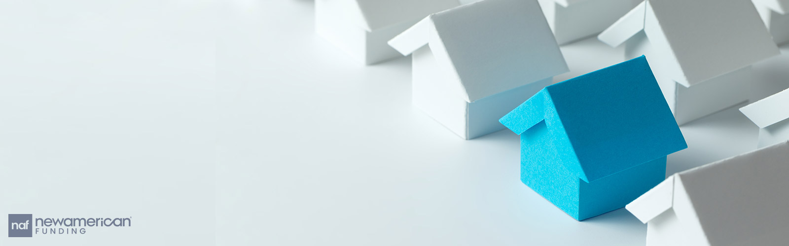 Several small paper models of houses sit on a table top