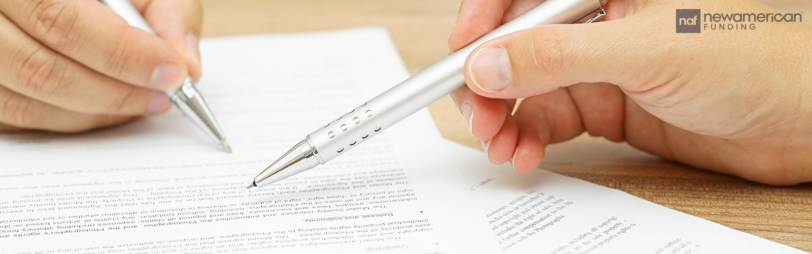 A photo of two hands signing paperwork 