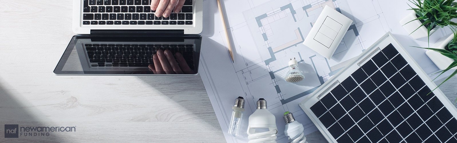 A laptop sits on a table top with schematics and various light bulbs