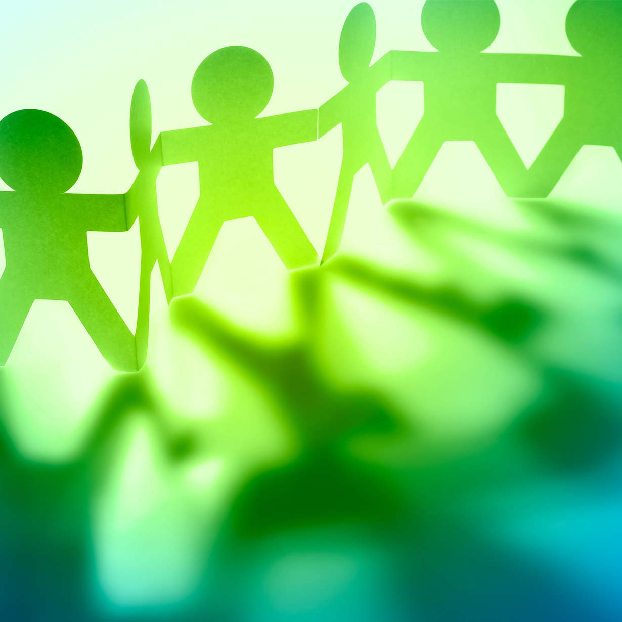 Close-up of a paper chain of green human figures symbolizing teamwork and connection