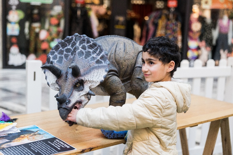 Boy playing with triceratops robot