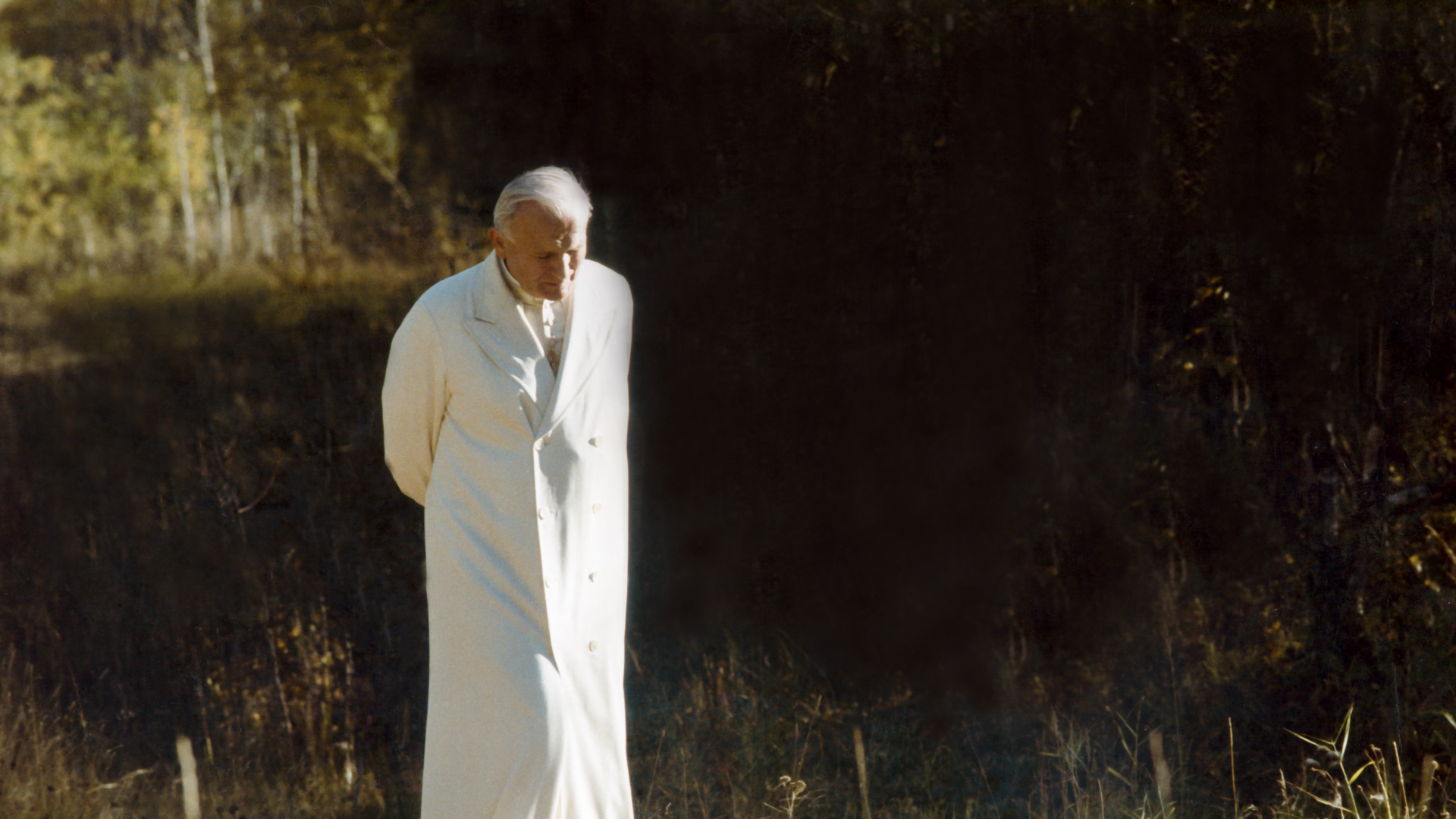 Pope John Paul II walks down a gravel path 