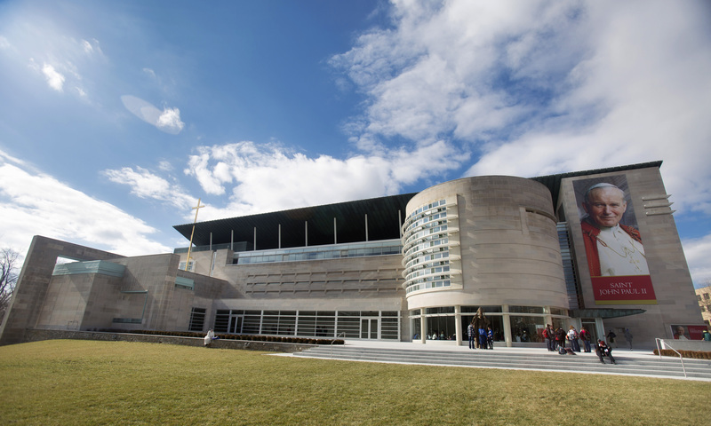 A wide view from the outside of the John Paul II National Shrine with people gathered near the entrance
