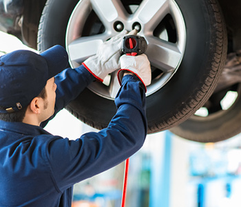Mehanik v vulkanizerski delavnici zaključuje premontažo gum na vozilu.