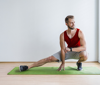 Mlad moški v svoji dnevni sobi med zimo izvaja vaje za moč in stabilnost - da bo v novi sezoni tekel še bolje
