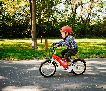Oče uči otroka voziti kolo na mirni poti v naravi.