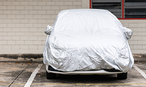 Avto - pripravljen na daljše mirovanje, je voznik prekril s pregrinjalom in parkiral pod streho.