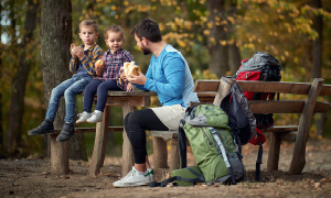 Kam na izlet z otrokom - oče se je na izletu z dvema majhnima otrokoma ustavil, da so skupaj pojedli malico.