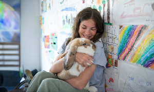 Najstnica ljubeče stiska domačega ljubljenčka - velikega zajca, ki ji sedi v naročju.