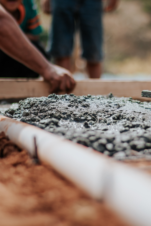 People working on a concrete walkway, construction site with workers and tools.