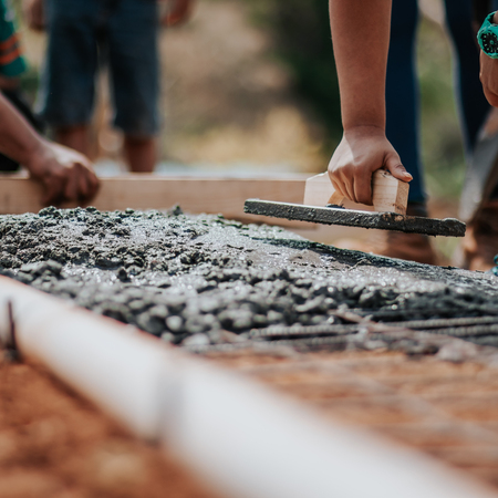 People working on a concrete walkway, construction site with workers and tools.