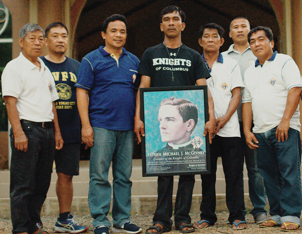 Holding an image of Father Michael J. McGivney, Rentegrado stands with fellow members of Council 14302, including Past Grand Knight Almer Ratuita (in blue shirt).