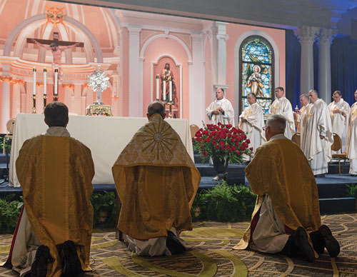 Archbishop Lori kneels in adoration before the exposed Blessed Sacrament.
