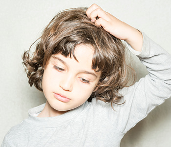 Deček se praska po glavi zaradi naglavnih uši