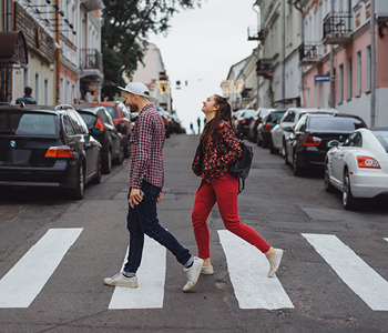 Mlad par prečka cesto na manjši mesti nulici.