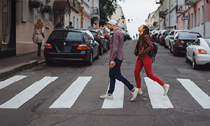 Mlad par prečka cesto na manjši mestni ulici.