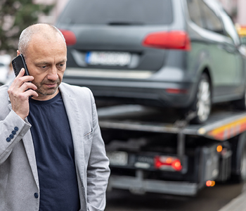 Zaposleni na sliki telefonira, medtem ko je avtovleka naložila in odpeljala njegov službeni avto zaradi okvare po nesreči.
