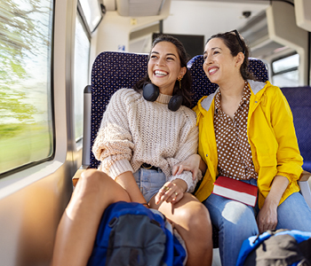 Dekleti odkrivata Evropo z vlakom in uživata v lepih razgledih trajnostnega in udobnega potovanja.