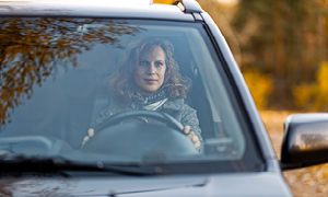 Ženska v avtomobilu je za volanom zelo zbrana, saj se zaveda nevarnosti jesenske vožnje.