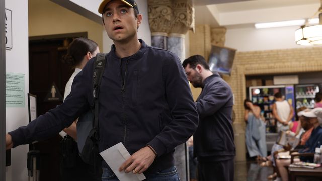 Dr. Frank Langdon stands in a busy hospital hallway looking concerned.
