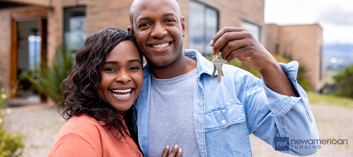 A smiling couple holds up keys.