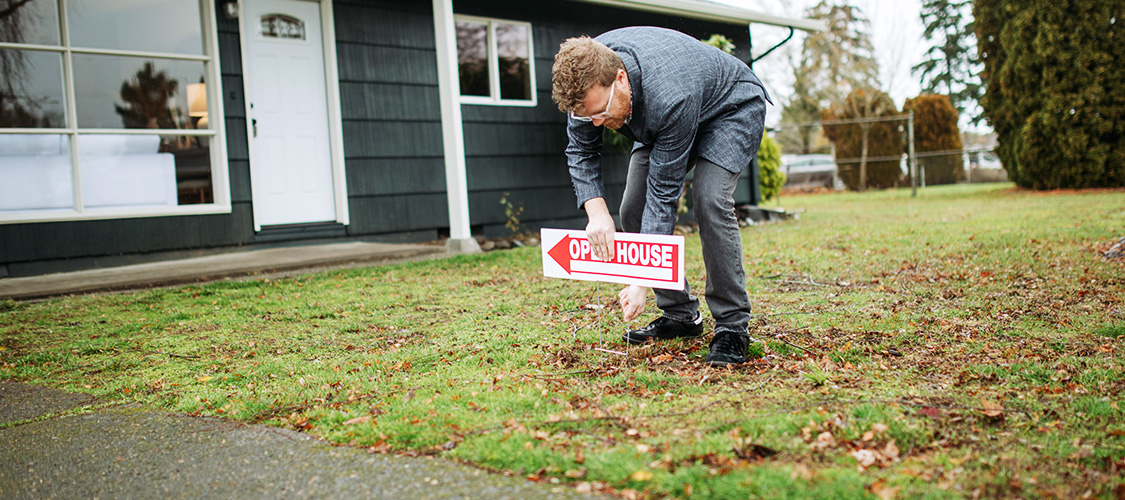 Real estate agent putting an open house sign in a yard