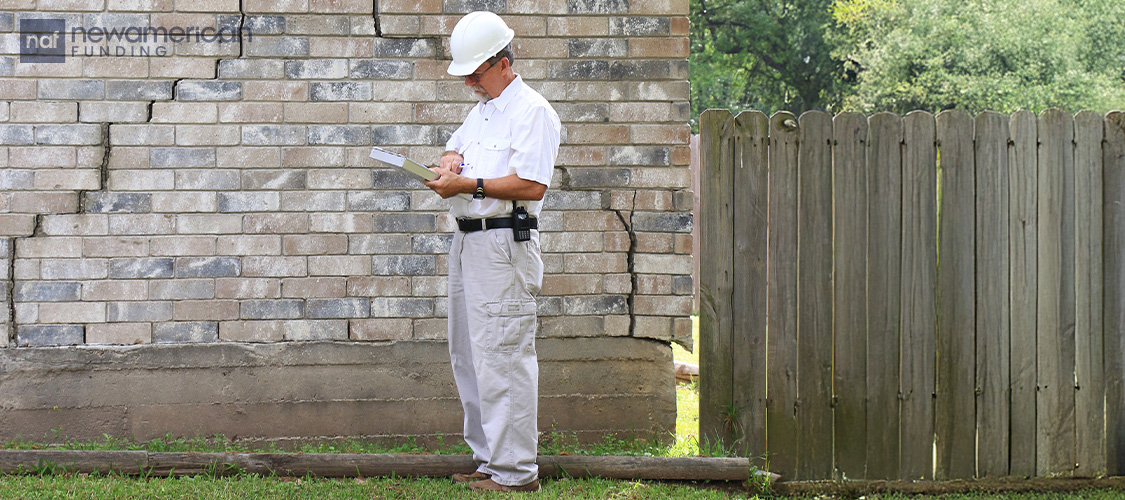 A home inspector looking at cracks in a brick wall of a home.