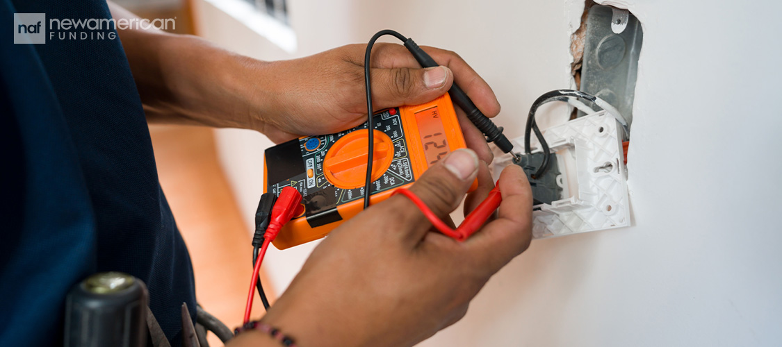 Someone testing an electrical socket with a device.