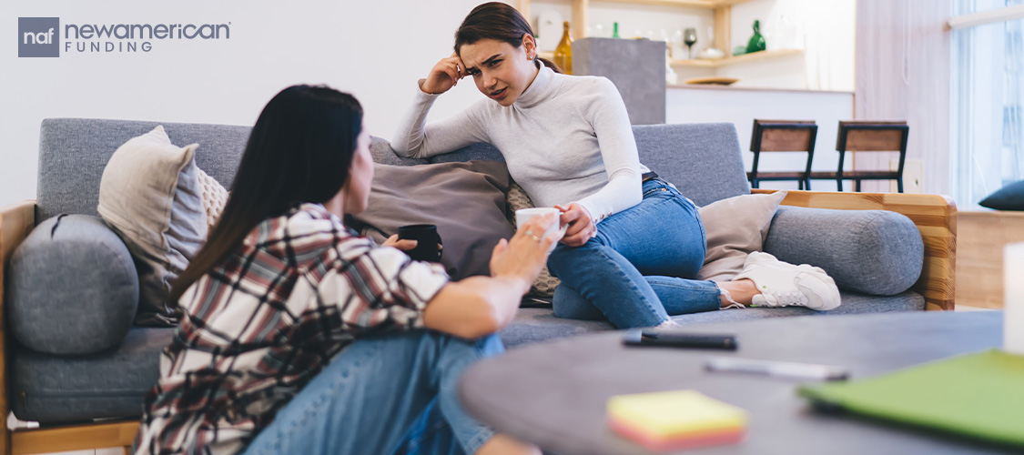 one sister sits on the couch, while the other sites on the floor