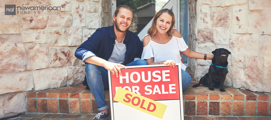 A couple sitting on steps with a sold sign.