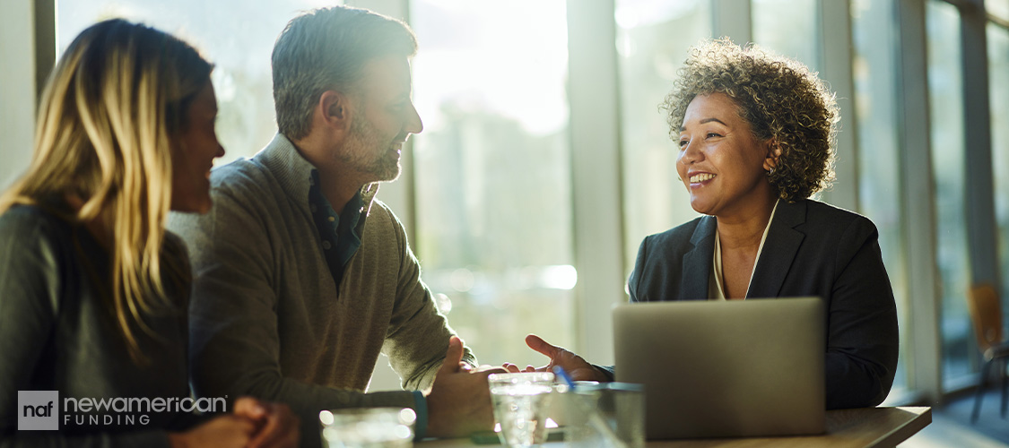 A couple smiling as they meet with a loan officer.