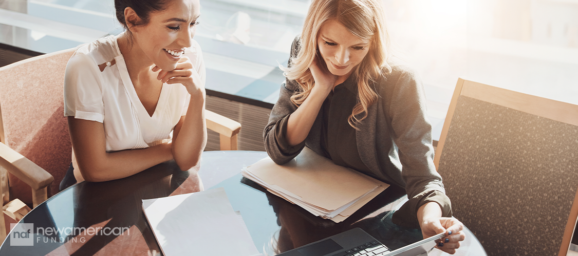 A woman showing another woman some paperwork.