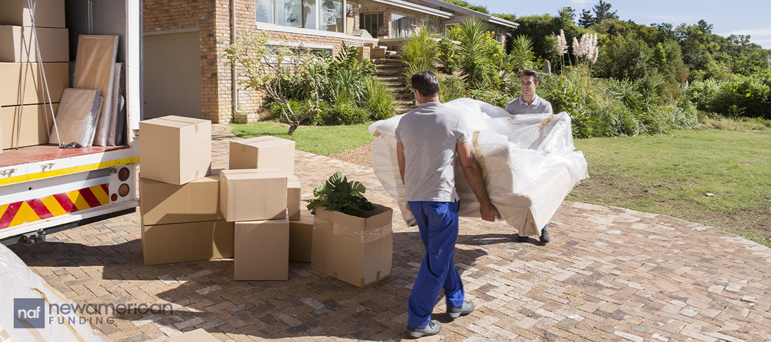 Young men carrying a couch onto a moving truck.