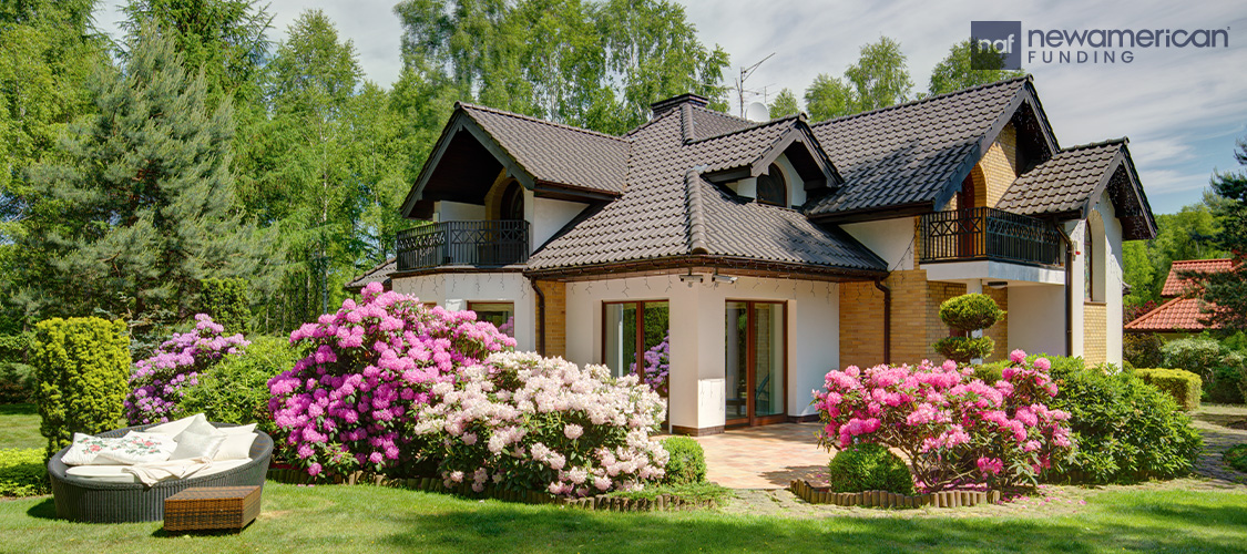 A large house with beautiful, flowering bushes surrounding it.