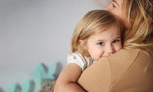 Deklica se skriva v maminem objemu in nagajico smehlja - podkožna bulica je ne skrbi, saj so ju zdravniki pomirili.